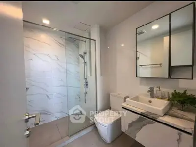 Modern bathroom with glass shower and sleek vanity in luxury apartment.