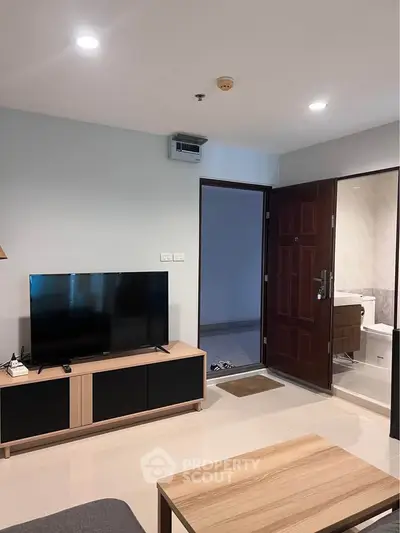 Modern living room with TV and open bathroom door in stylish apartment