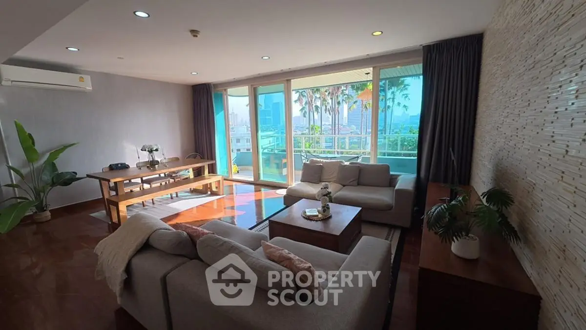 Spacious living room with large windows and modern decor in a high-rise apartment.
