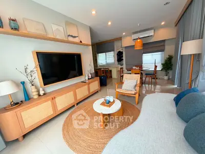 Stylish modern living room with cozy seating and large TV, perfect for relaxation and entertainment.