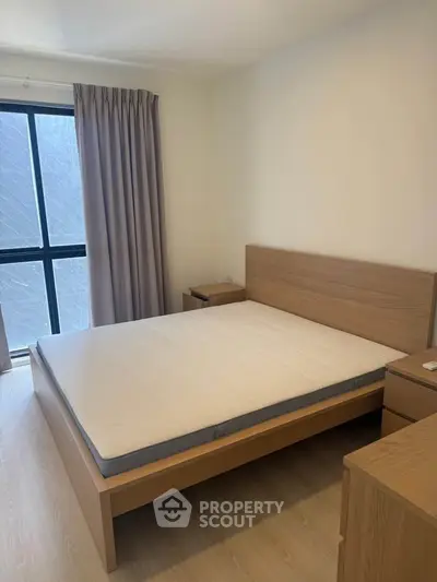 Spacious bedroom with modern wooden furniture and large window for natural light.