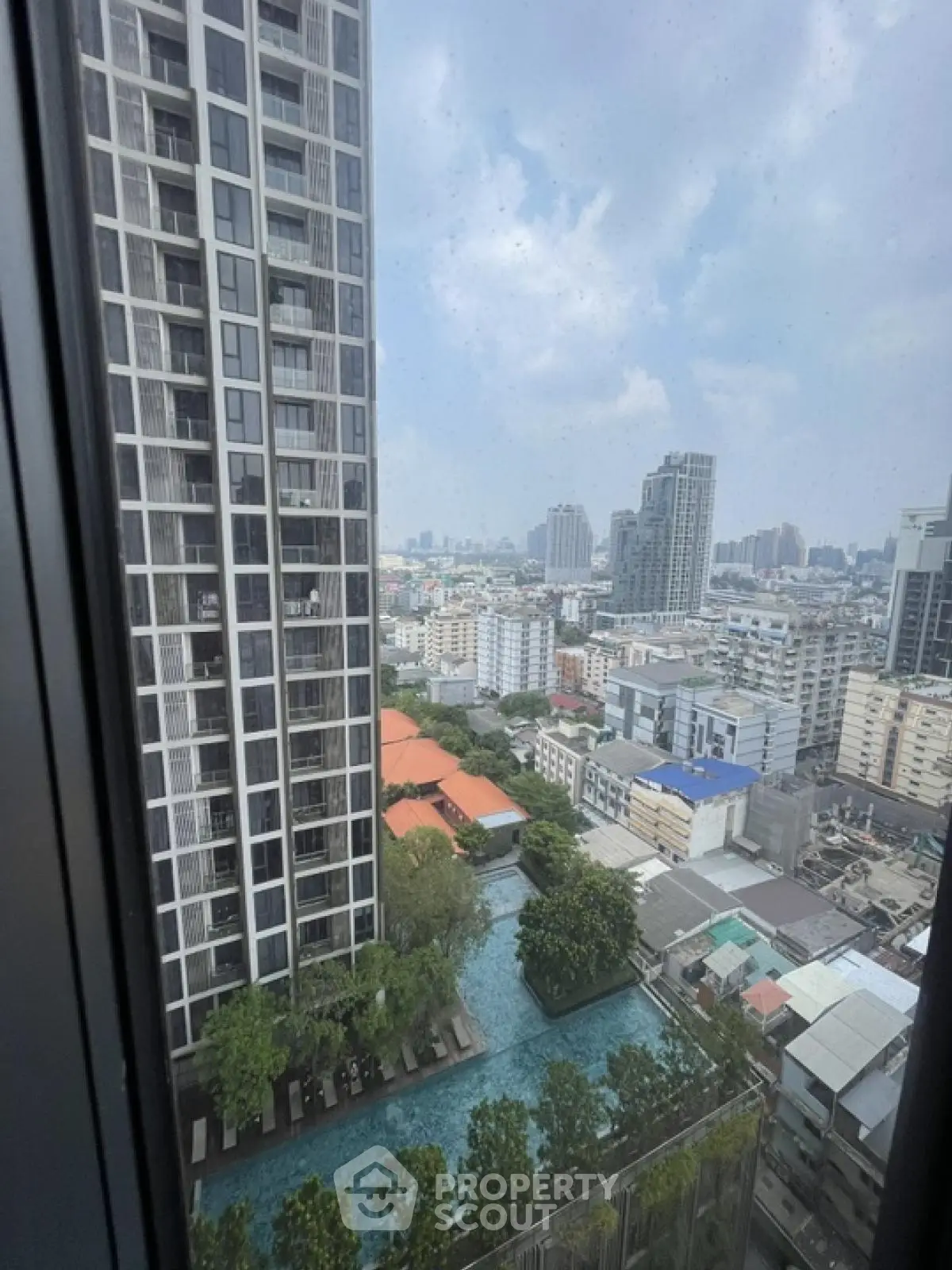 Stunning cityscape view from high-rise apartment with pool and modern architecture.