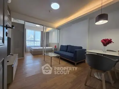 Modern open-plan living room with cozy seating and dining area, featuring stylish decor and natural light.