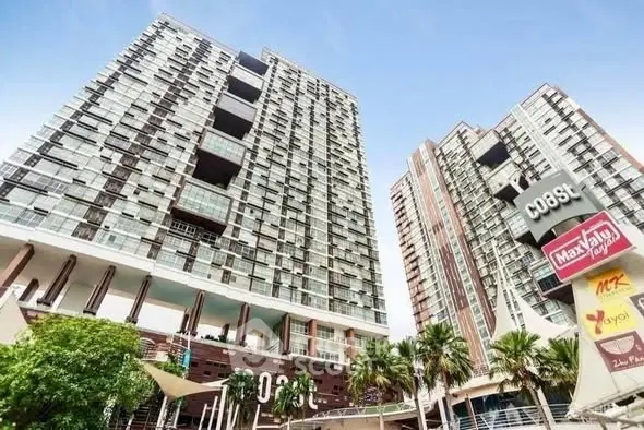 Modern high-rise residential buildings with retail signage and lush greenery.