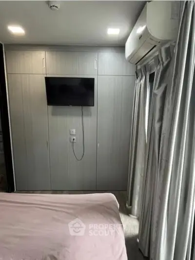 Modern bedroom with built-in wardrobe and wall-mounted TV, featuring air conditioning and elegant curtains.