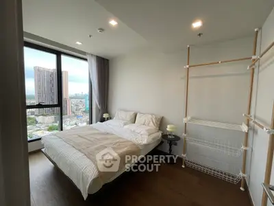 Modern bedroom with city view, featuring minimalist decor and large window for natural light.