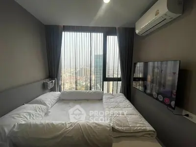 Modern bedroom with city view, featuring a wall-mounted TV and air conditioning.