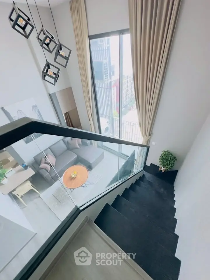 Modern duplex apartment with stylish staircase and floor-to-ceiling windows offering city views.