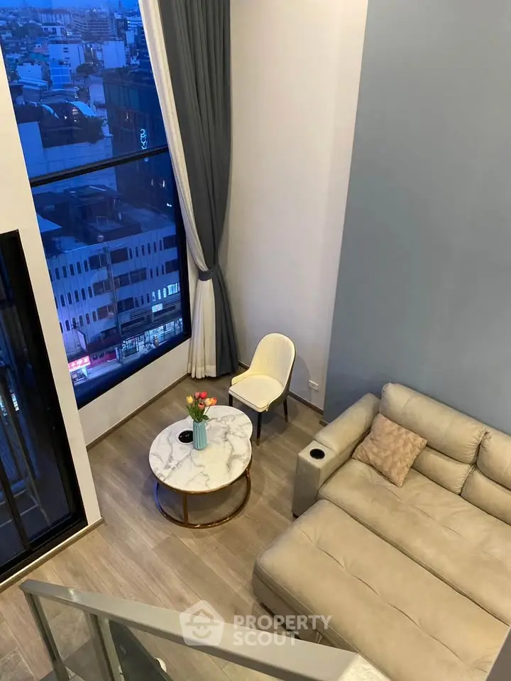 Modern living room with high ceiling and city view, featuring a cozy sofa and elegant decor.