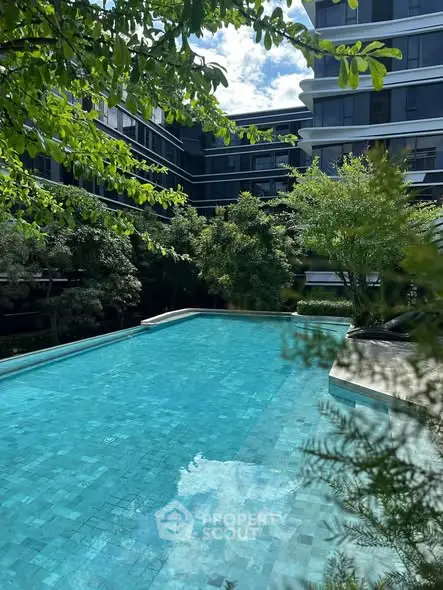 Luxurious residential pool surrounded by lush greenery and modern architecture.