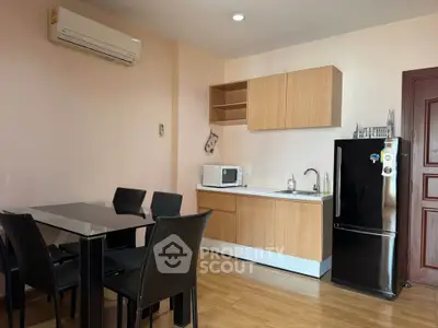 Modern kitchen with dining area, featuring sleek black chairs and compact appliances.