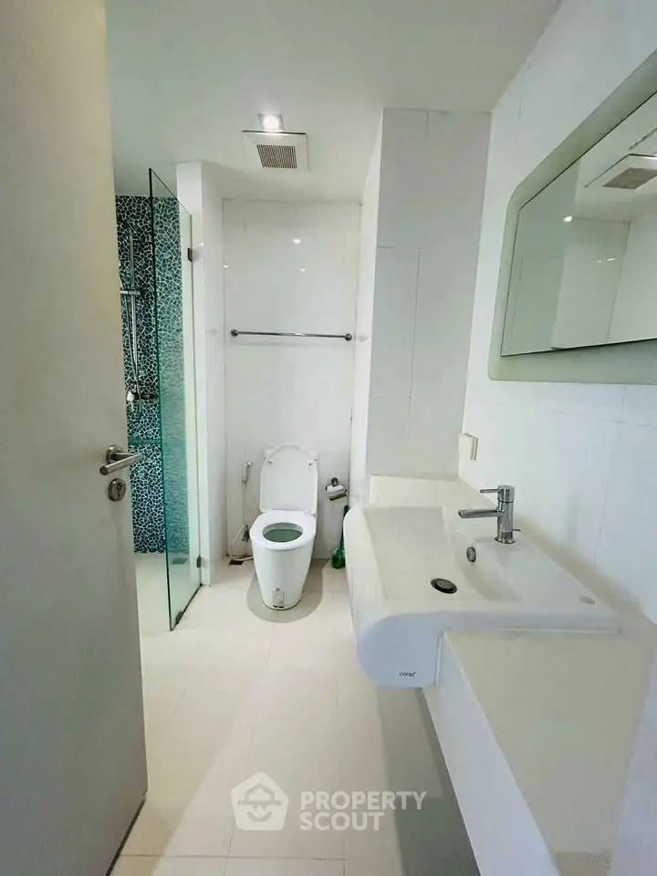 Modern bathroom with sleek white fixtures and glass shower enclosure