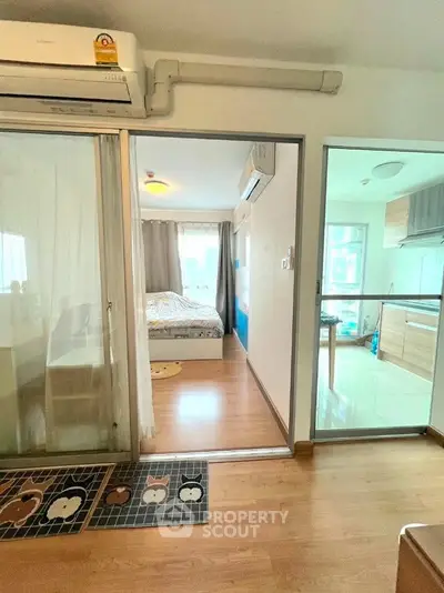 Cozy apartment interior with bedroom and kitchen, featuring wooden flooring and modern decor.