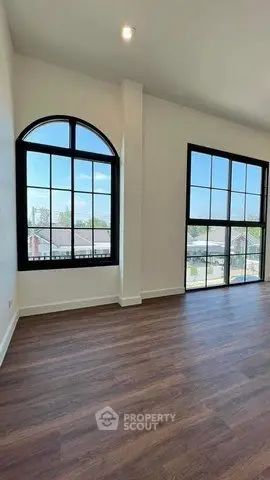 Spacious living room with large arched windows and elegant wood flooring.
