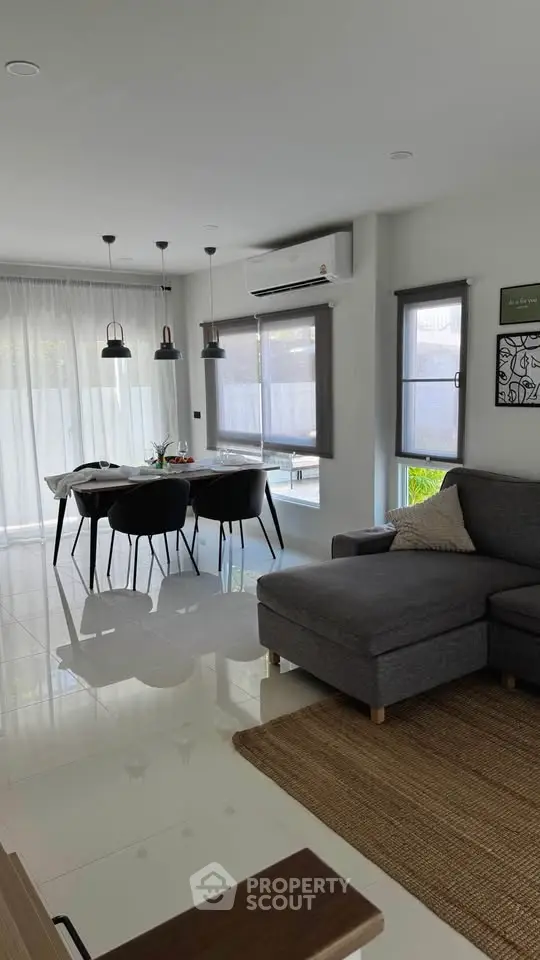 Modern living room with dining area, featuring sleek furniture and abundant natural light.