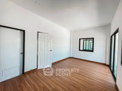 Spacious empty room with wooden flooring and white walls, ideal for customization.