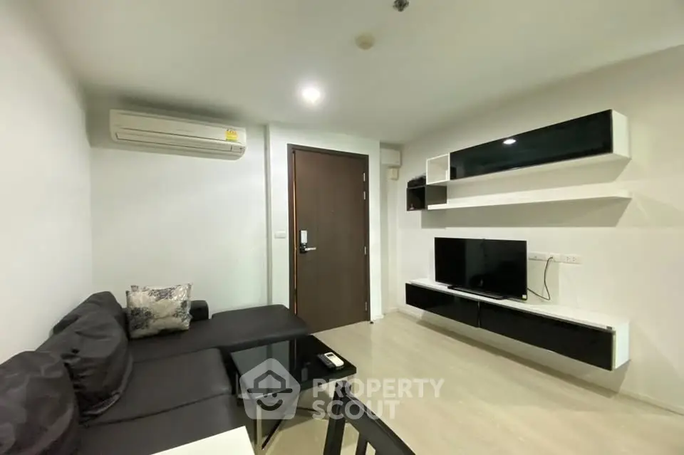 Modern living room with sleek furniture and wall-mounted TV in a cozy apartment.