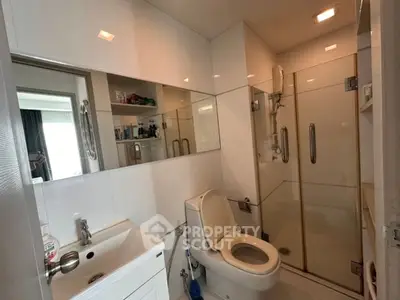 Modern bathroom with glass shower and sleek white fixtures.