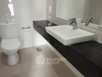 Modern bathroom with sleek fixtures and elegant black countertop.
