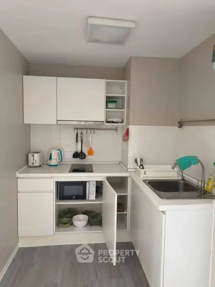 Compact kitchen with modern appliances and open shelving in a cozy apartment.