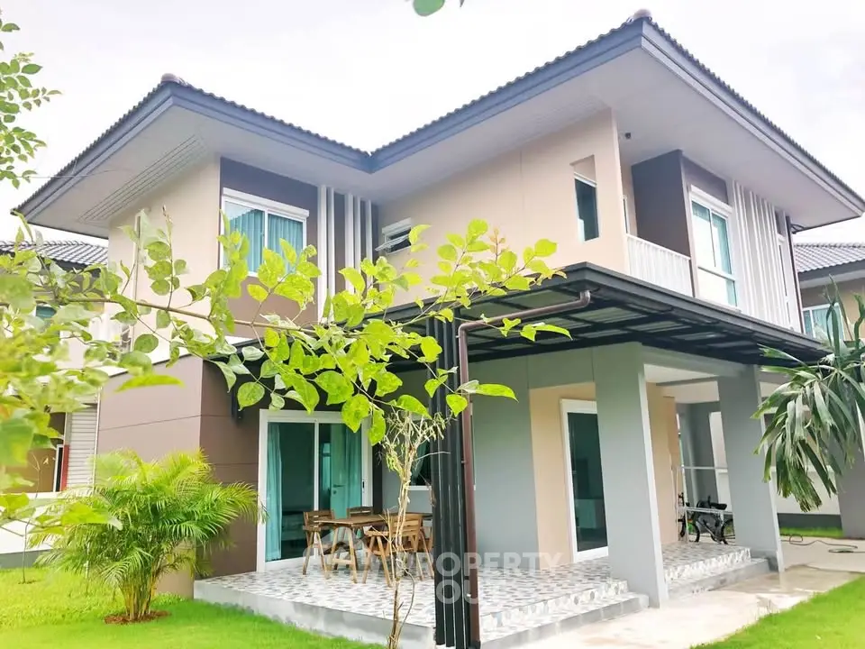 Modern two-story house with lush garden and outdoor seating area.