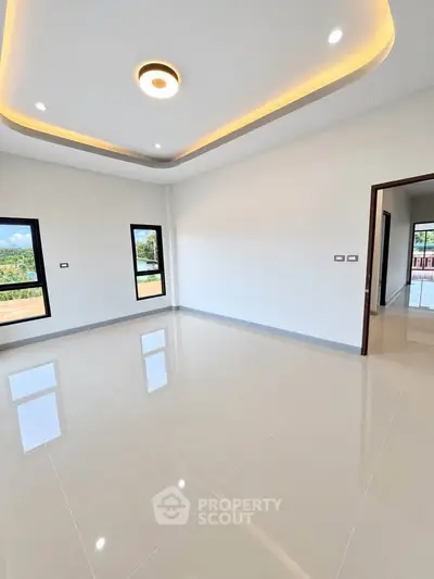 Spacious modern living room with elegant ceiling lights and large windows offering scenic views.