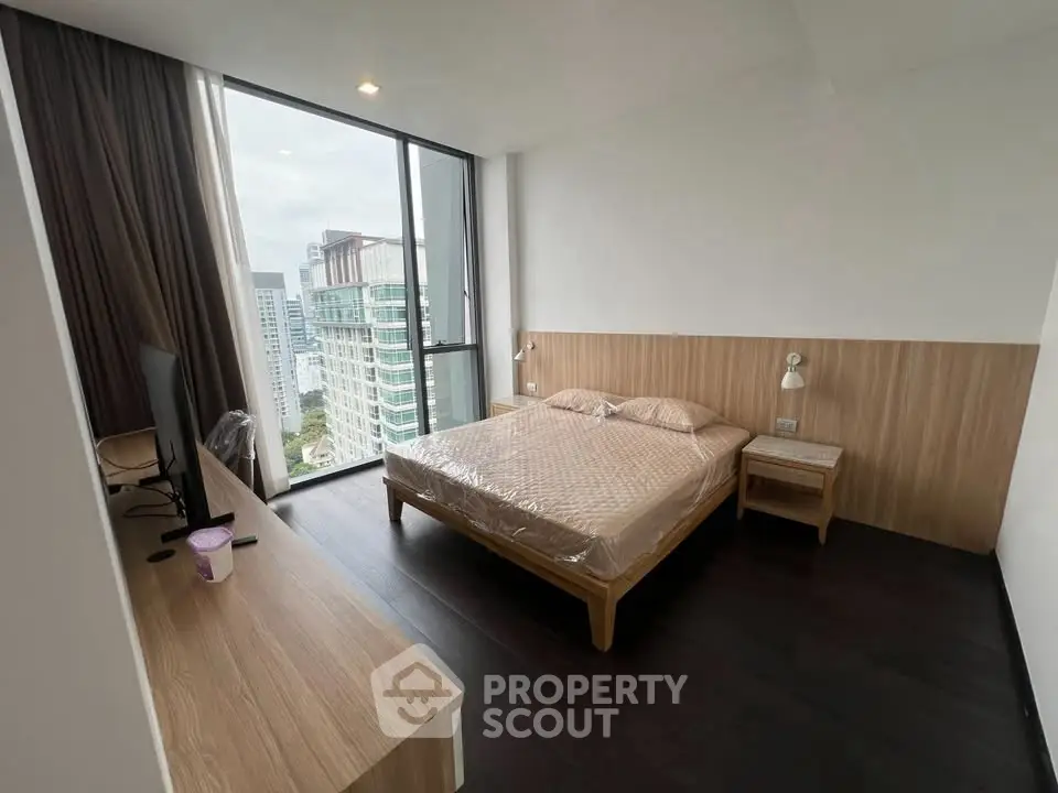 Modern bedroom with city view, featuring sleek furniture and large windows for natural light.