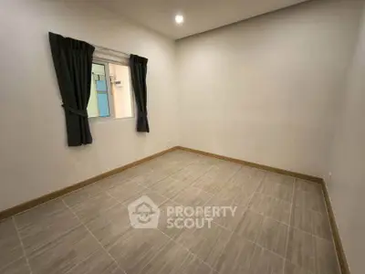 Spacious empty room with tiled flooring and window, ideal for customization.