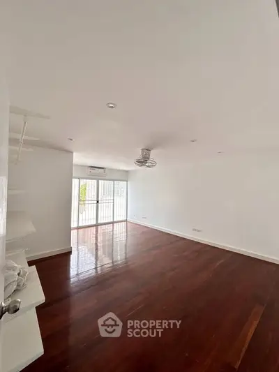 Spacious living room with wooden flooring and large windows for natural light.