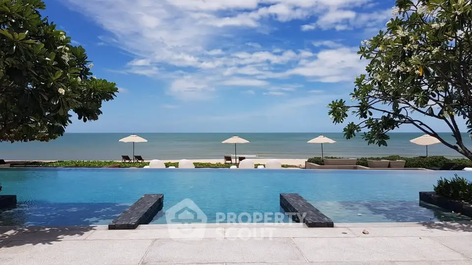 Luxurious beachfront infinity pool with stunning ocean view and lush greenery.