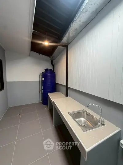 Modern utility area with sleek sink and water tank, perfect for efficient home management.