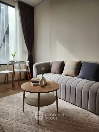 Modern living room with stylish sofa, elegant coffee table, and natural light from large window.