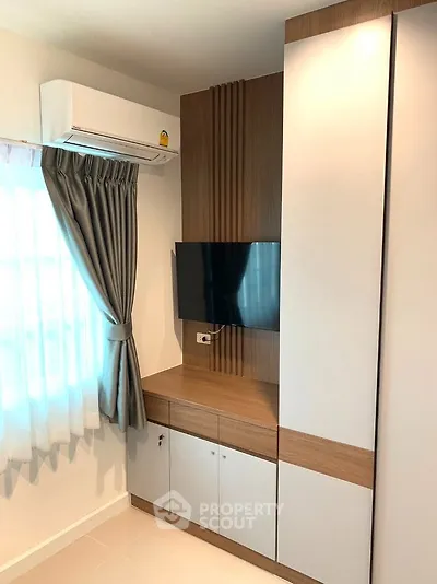 Modern living room corner with wall-mounted TV and stylish cabinetry.