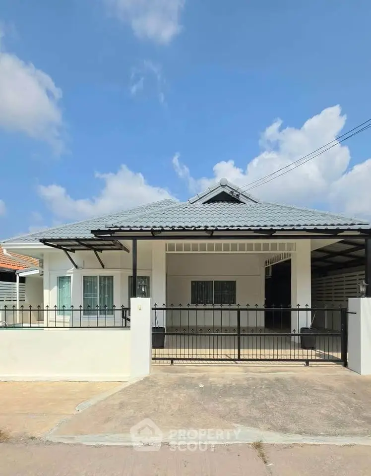 Charming single-story house with modern design and spacious driveway under a clear blue sky.