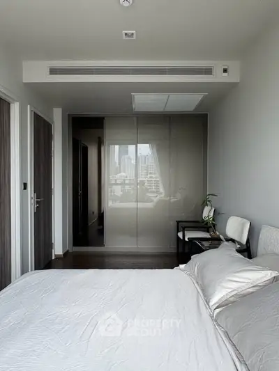 Modern bedroom with sleek design and city view, featuring a comfortable bed and stylish decor.