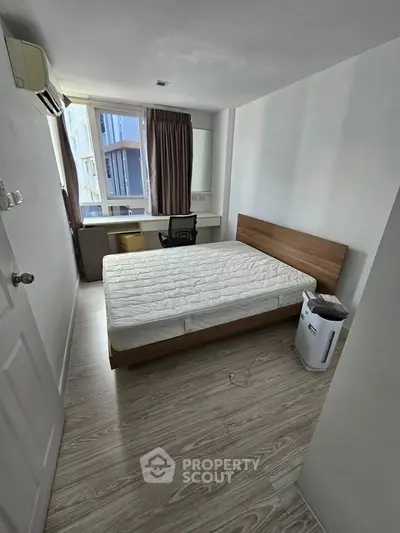 Cozy bedroom with natural light, featuring a comfortable bed and study area, perfect for urban living.
