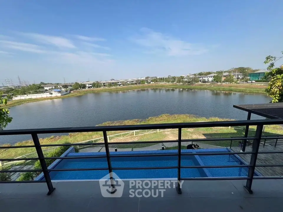 Stunning balcony view overlooking serene lake and pool in modern residential area.