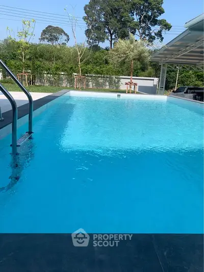 Luxurious outdoor swimming pool with crystal clear water and lush greenery, perfect for relaxation and leisure.