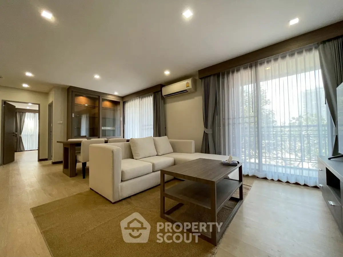Spacious living room with modern furniture and large windows in a well-lit apartment.