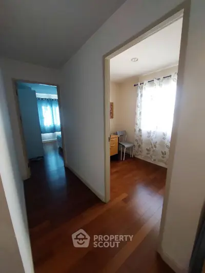 Bright hallway leading to cozy bedrooms with wooden flooring and natural light.