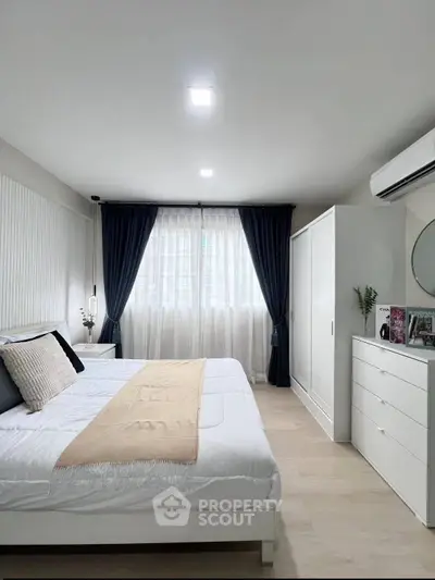 Modern bedroom with elegant decor, featuring a cozy bed, stylish wardrobe, and natural light from large windows.
