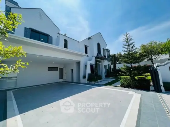 Luxurious modern villa with spacious driveway and lush garden, perfect for upscale living.