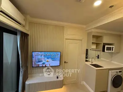 Modern apartment interior with compact kitchen and living area, featuring washing machine and TV.