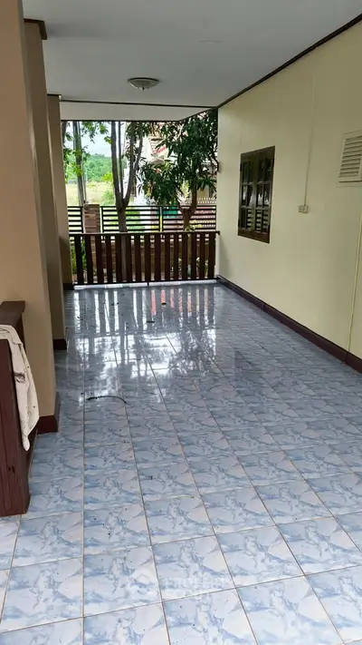 Spacious tiled balcony with wooden railing and garden view