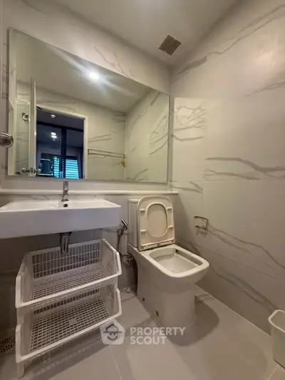 Modern bathroom with sleek design and large mirror in a contemporary apartment.