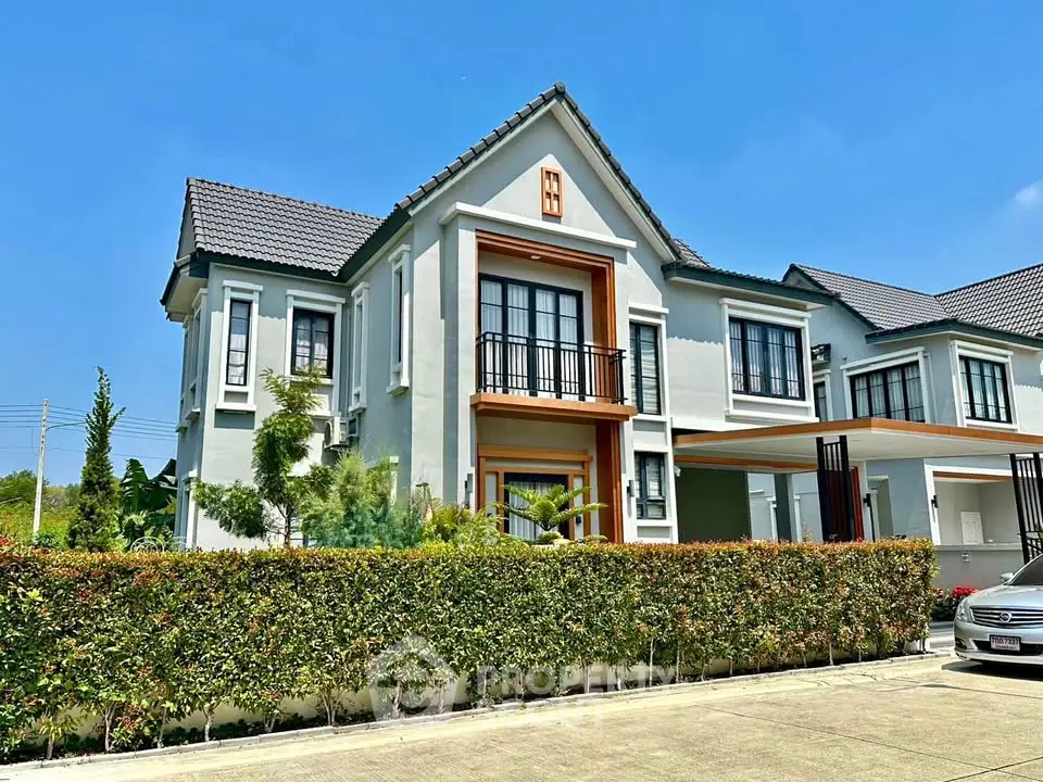 Stunning modern two-story house with manicured garden and spacious driveway under clear blue sky.