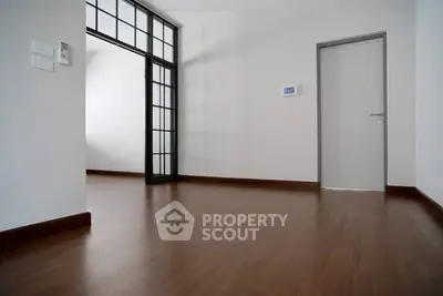 Spacious modern interior with wooden flooring and glass partition, ideal for versatile living spaces.