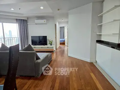 Spacious living room with modern decor and city view, featuring hardwood floors and stylish furniture.