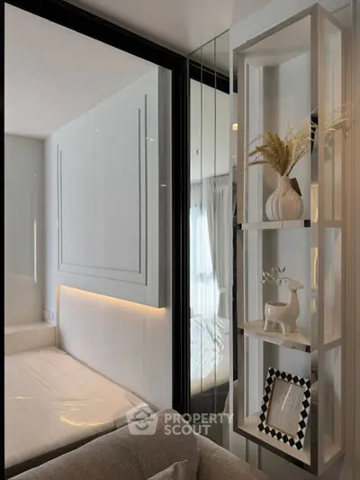 Modern bedroom with stylish decor and natural light, featuring a cozy bed and elegant shelving.