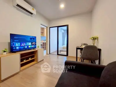 Modern living room with sleek furniture and open layout, featuring a TV and air conditioning.